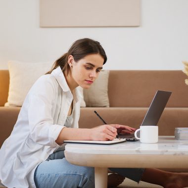 young-woman-using-laptop-and-taking-notes