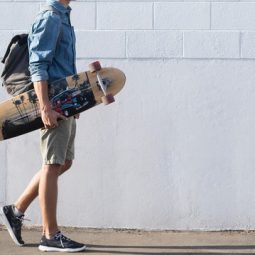 pria sedang berjalan dan memegang skateboard